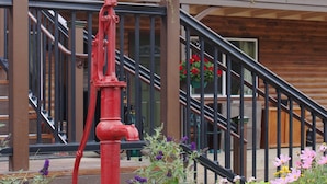 Un edificio de madera con balcón, un hidrante rojo y macetas colgantes de flores.