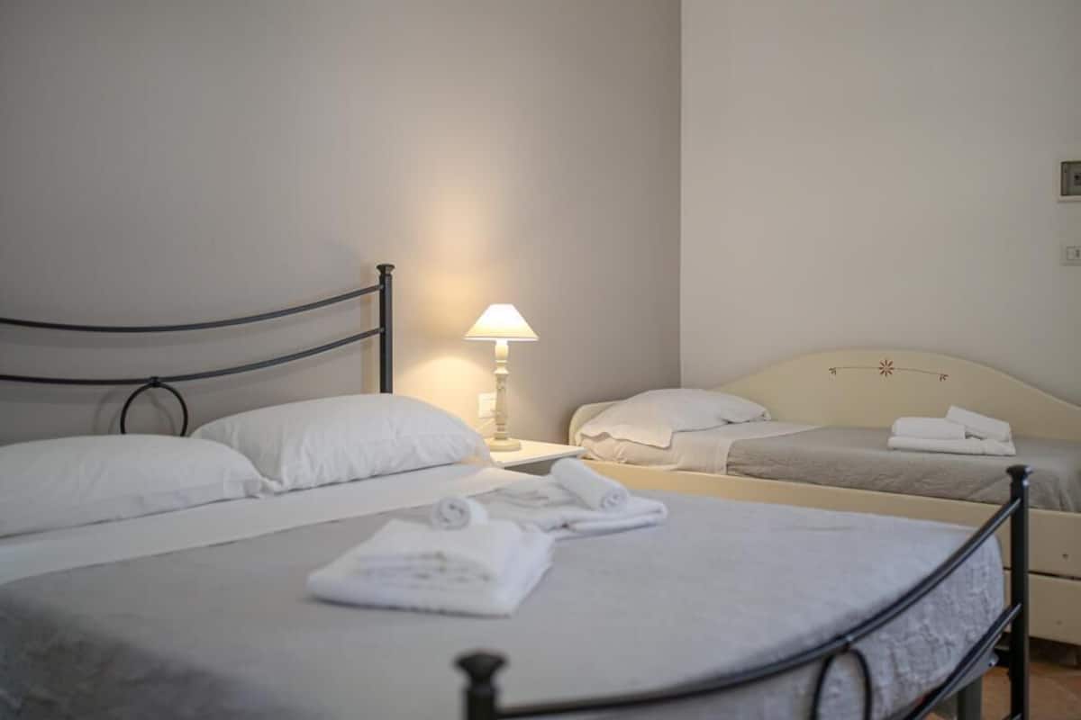 A hotel room with two beds, a nightstand with a lamp, and neatly folded towels on the beds.