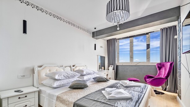 Un dormitorio moderno con una cama grande, un tocador y una ventana con cortinas.