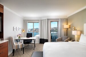 Habitación de hotel con cama, escritorio, sillas y vistas a la ciudad.
