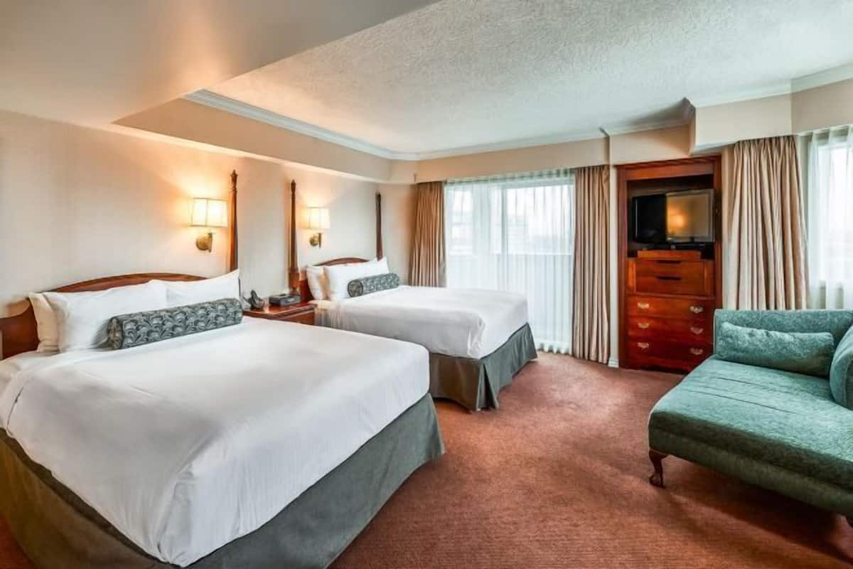 A hotel room with two beds, a sofa, a TV, and a dresser.