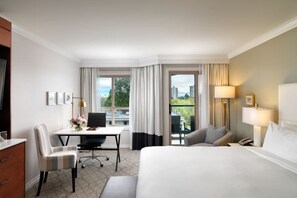 Et hotelværelse med seng, skrivebord, stol og udsigt til det fri.