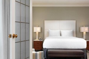 Habitación de hotel con una cama grande, dos mesitas de noche y una puerta con manija.