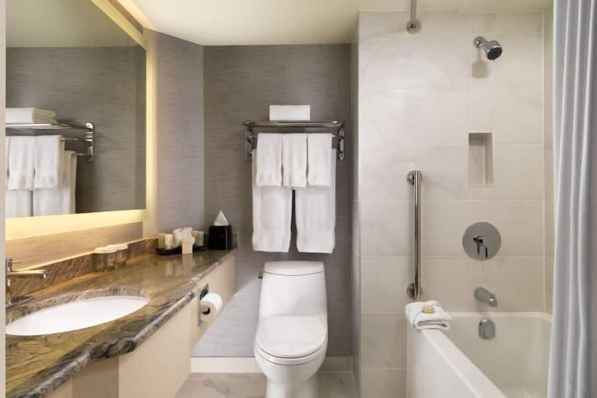 A modern bathroom with a marble sink, white toilet, and a walk-in shower.