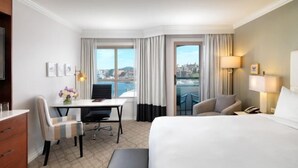 Ein Hotelzimmer mit Bett, Schreibtisch, Stuhl, Esstisch und Blick auf die Stadt.