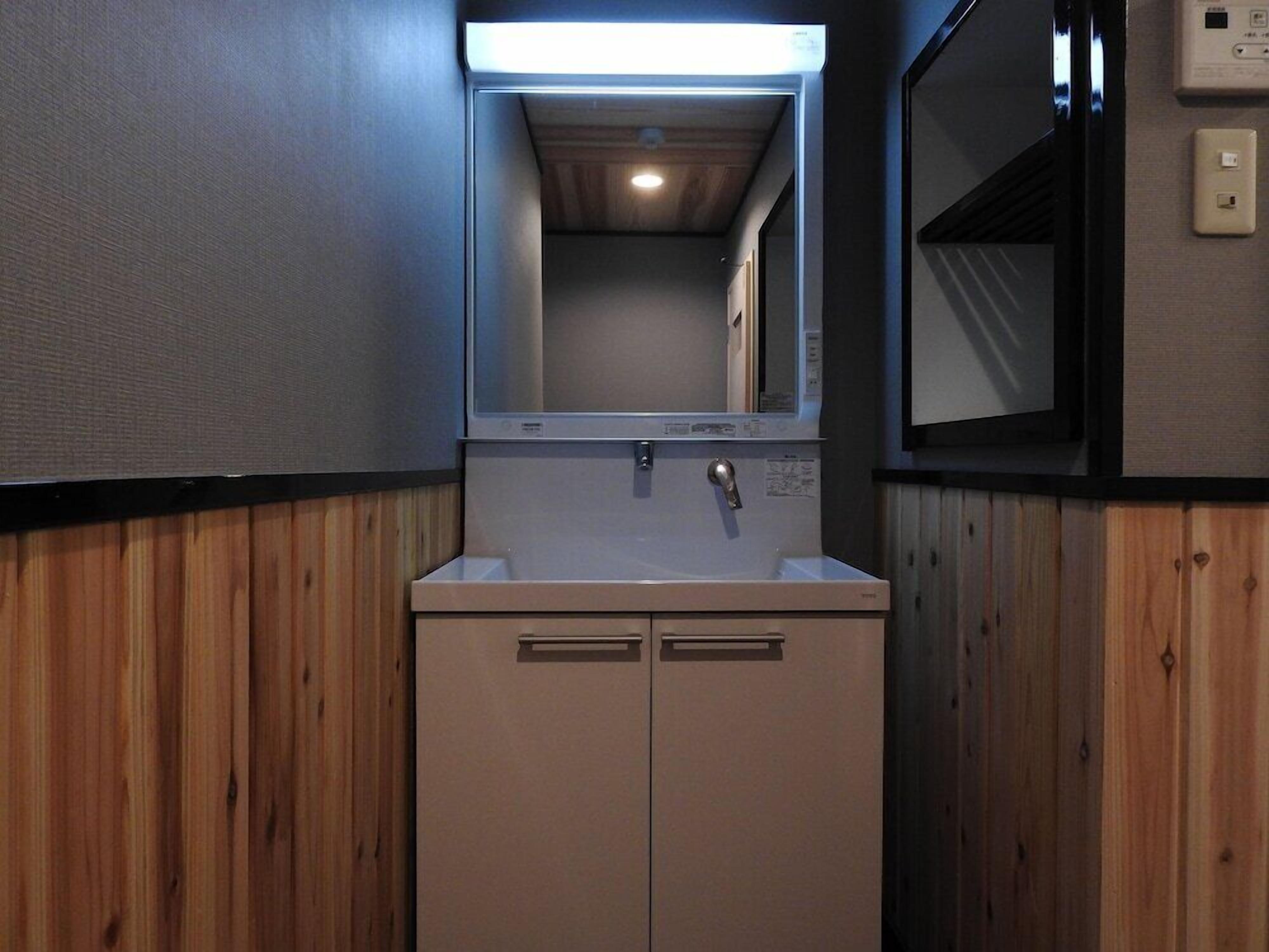 A bathroom with a sink, mirror, and wooden paneling.