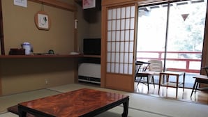 A tatami mat room with a wooden table and chairs, a television, and a sliding door leading to an outdoor area. - Sekishoin (Koya)