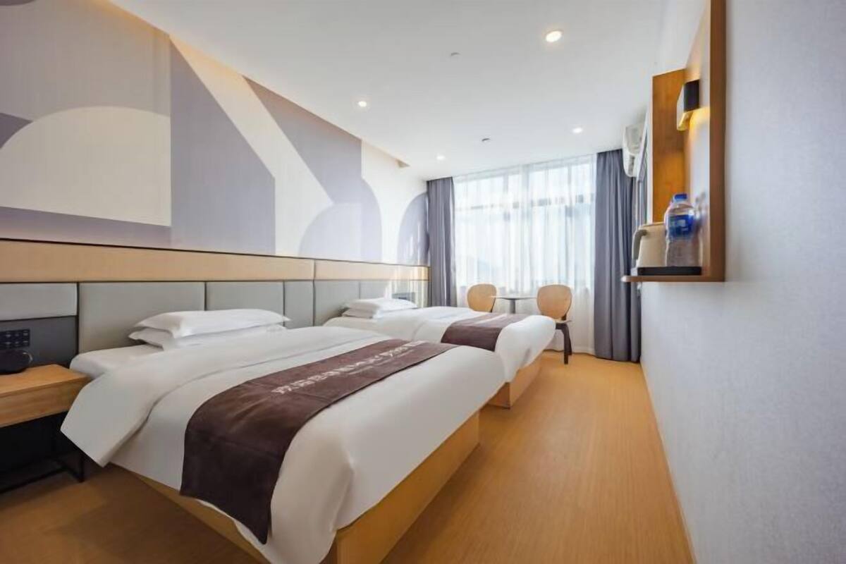 A hotel room with two beds, a desk, a chair, and a small table.