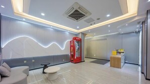 Eine moderne Lobby mit einer gebogenen Sitzgruppe, einem Verkaufsautomaten und einer Rezeption.