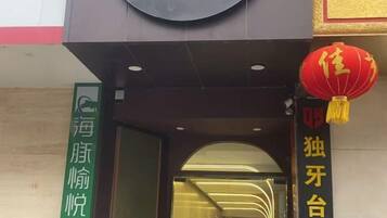 A hotel entrance with a green sign and a red lantern.