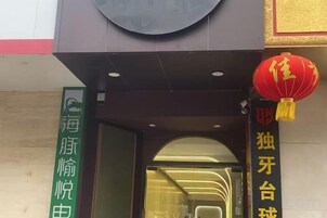 Entrada de hotel com uma placa verde e um lanterna vermelha.