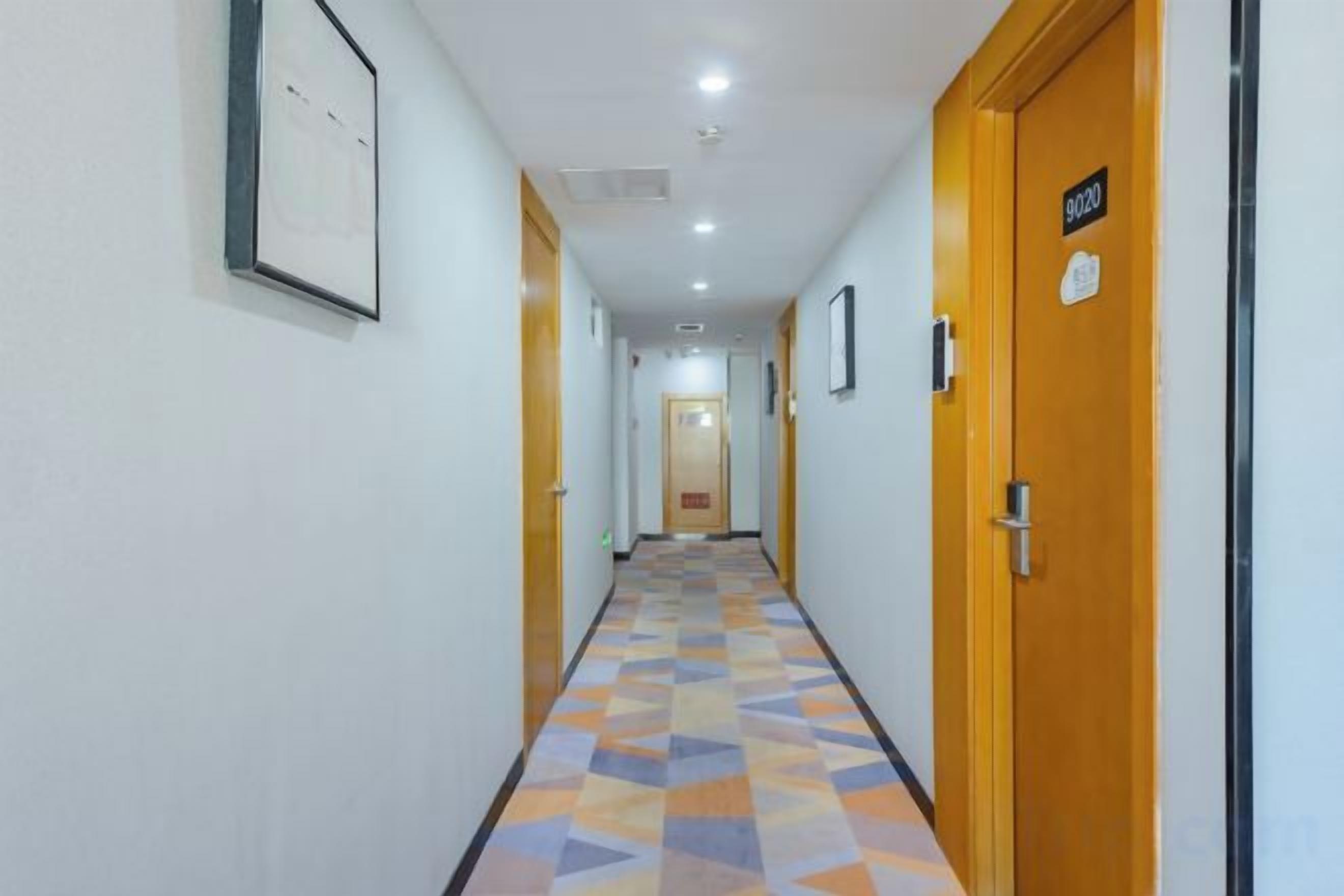 A hotel corridor with doors, a patterned floor, and a ceiling light.
