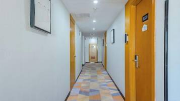 A hotel corridor with doors, a patterned floor, and a ceiling light.