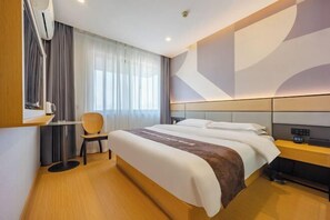 A modern hotel room with a large bed, a bedside table, a chair, and a window with curtains. - 7 Days Inn (Ningguo Ningcheng North Road) (Xuancheng)