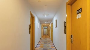 Ein Hotelkorridor mit Teppichmuster, Holztüren und einem Schild, das Zimmer Nummer 1003 anzeigt.