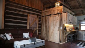 Ein rustikales Blockhaus-Interieur mit einer Essnische aus Holz, einer Couch mit Zierkissen und einer Kaffeestation.