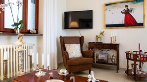A living room with a brown armchair, a wooden coffee table, a television, and a painting on the wall.