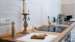 A kitchen counter with a white brick backsplash, a wooden cutting board, a white candle, and a small ceramic owl figurine.