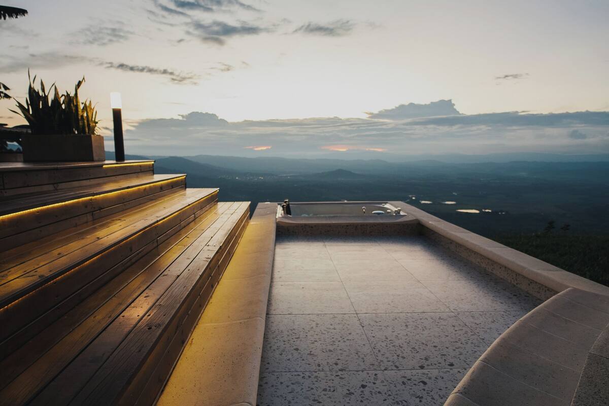 Un sentier de pierres mène à une piscine d’où l’on peut admirer la vue sur les montagnes lointaines.