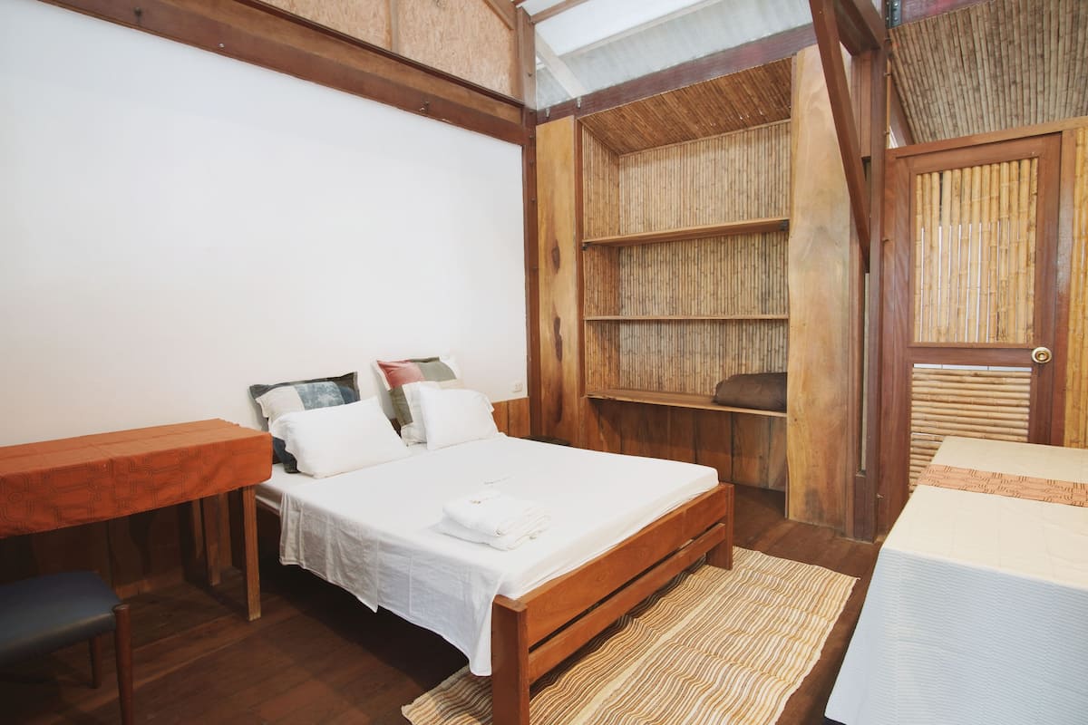 A wooden-framed bedroom with a bed, a bench, and a small table.