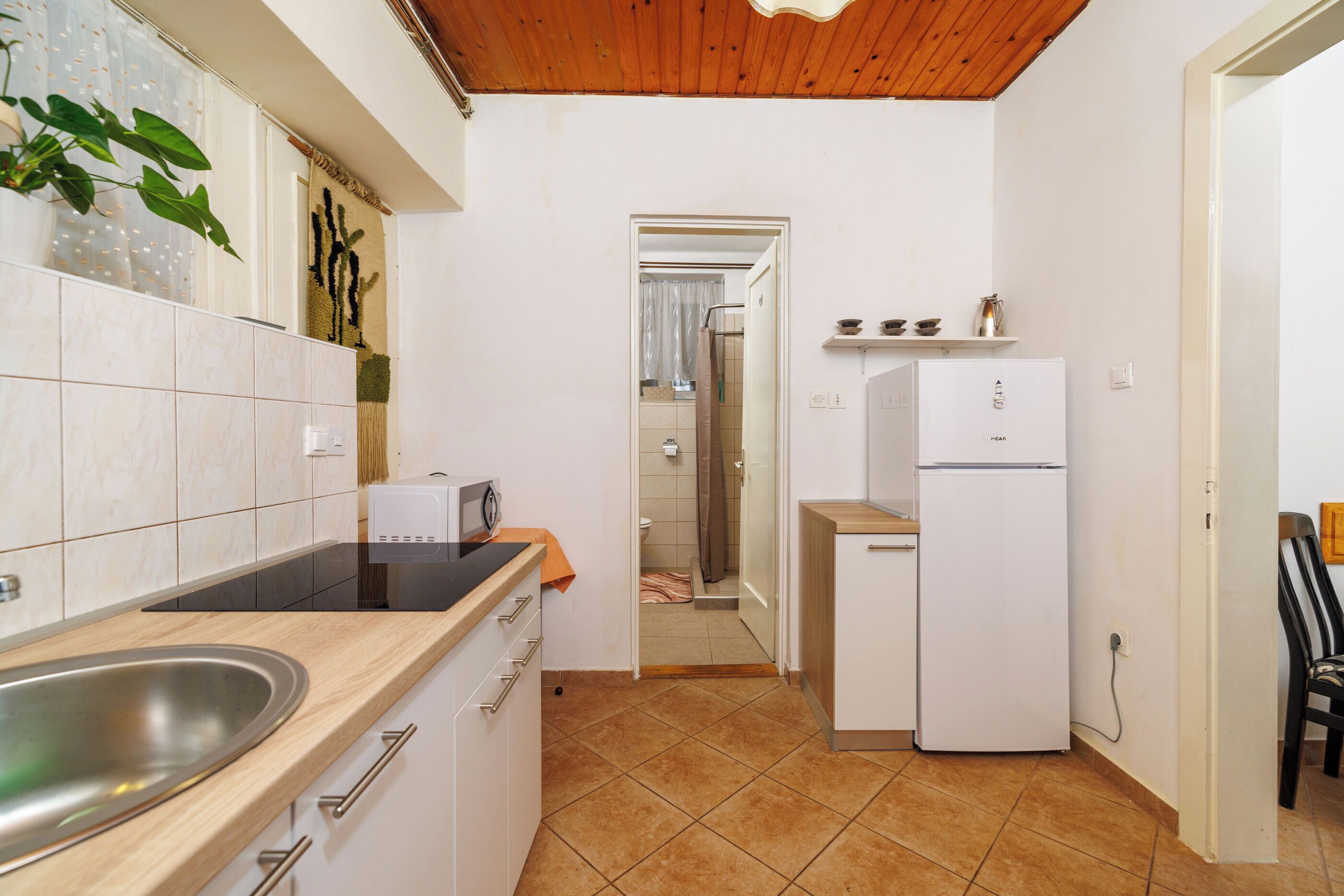Una cucina compatta con lavello, piano di lavoro e frigorifero bianco.
