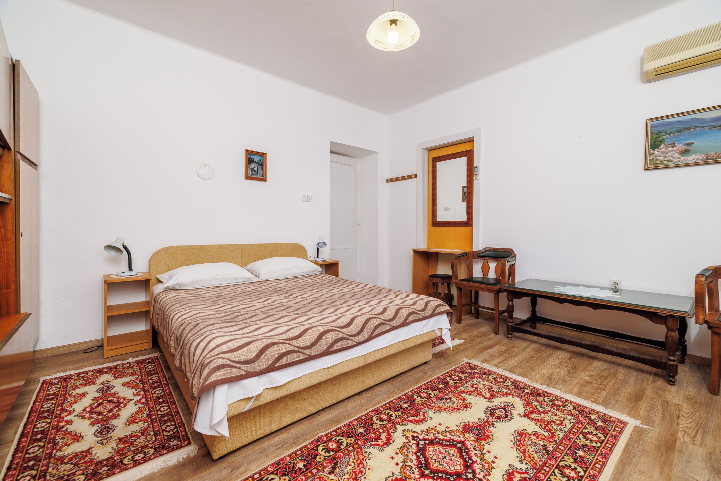A bedroom with a bed, bedside tables, a desk, and a chair.