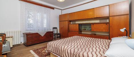 A bedroom with a large bed, wooden wardrobe, a desk, and a chair.