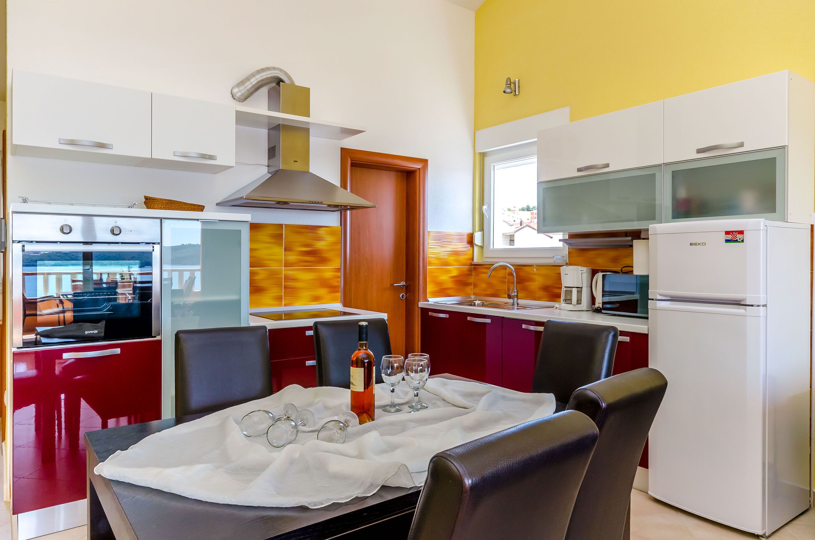 Eine moderne Küche mit Essbereich, ausgestattet mit Herd, Backofen, Mikrowelle und Kühlschrank.
