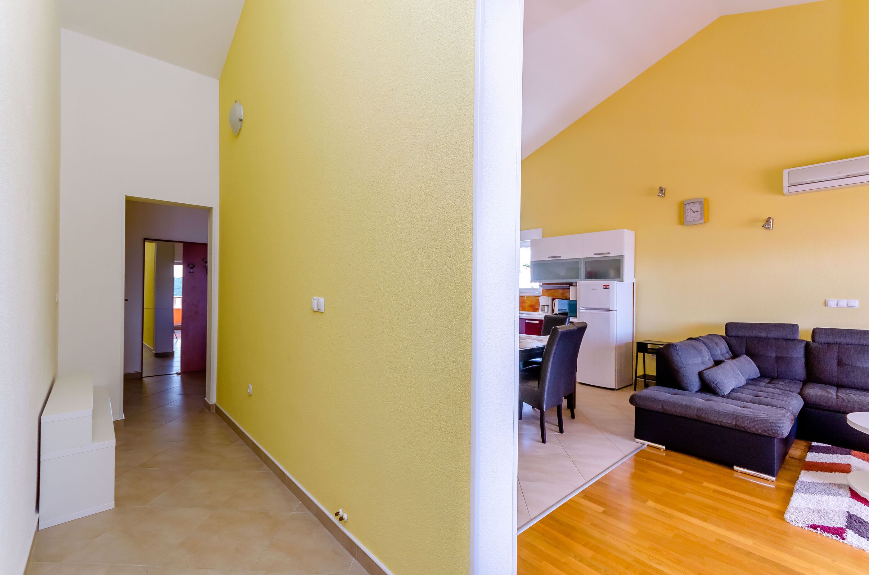 A living room with a sectional sofa, a dining area with a table and chairs, and a kitchen with appliances.