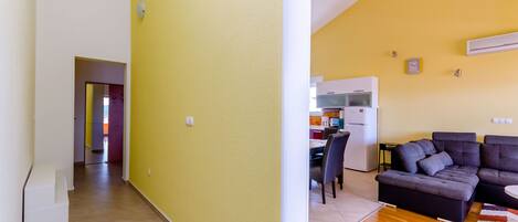 A living room with a sectional sofa, a dining area with a table and chairs, and a kitchen with appliances.