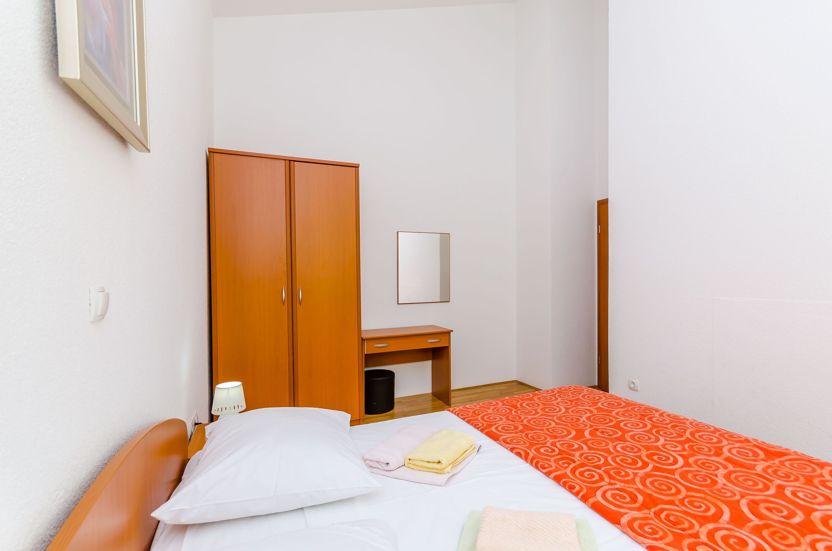 Una camera da letto con un letto, un armadio, un comodino e uno specchio.