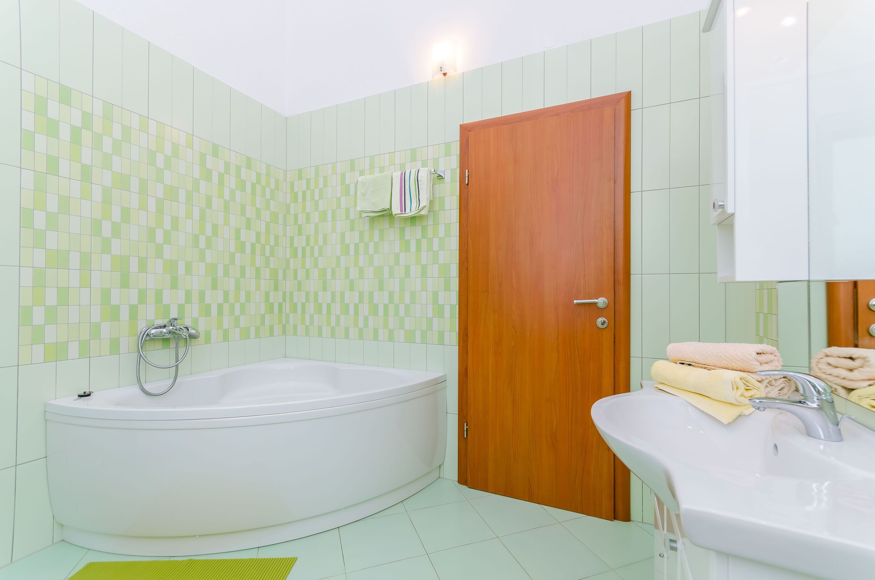 Een badkamer met een badkuip, wastafel en een houten deur.