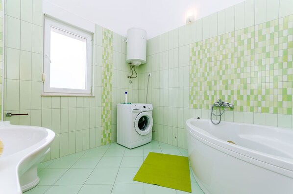 A bathroom with a washing machine, a bathtub, and a toilet. - Apartments Melita (Okrug Gornji)