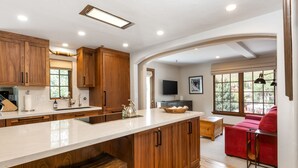 Une cuisine moderne avec des meubles en bois, un grand îlot central et un canapé rouge dans l’espace salon.