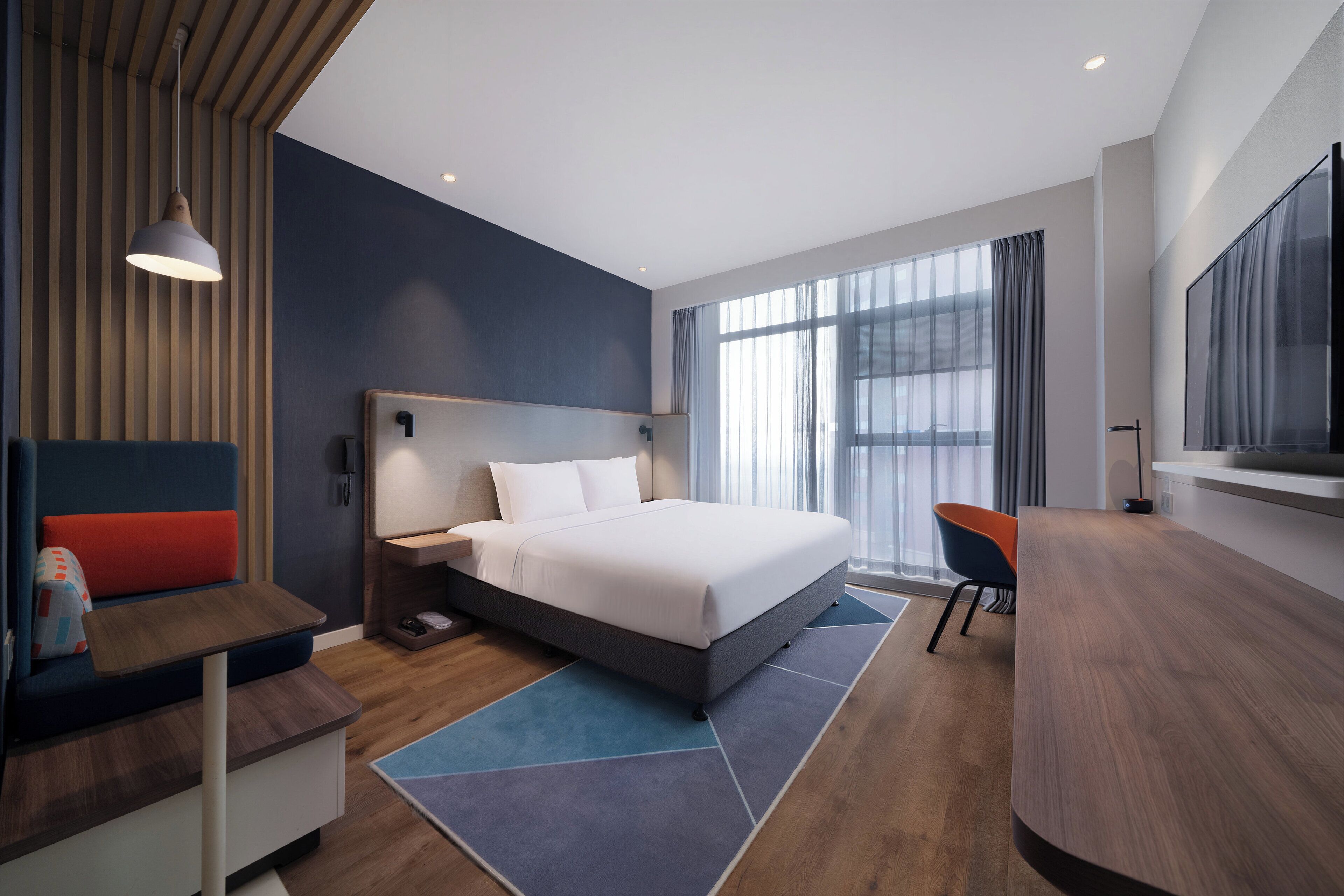 Une chambre d’hôtel moderne équipée d’un grand lit, d’un bureau, d’une chaise et d’un téléviseur.