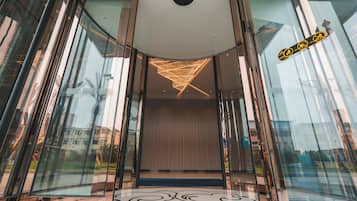 A modern entrance with glass doors, a patterned floor, and a decorative ceiling light fixture.