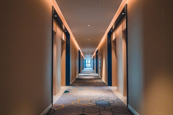 A long, narrow hotel corridor with a patterned carpet and recessed lighting. - Holiday Inn Express Pengzhou Downtown by IHG (Chengdu)