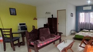Ein Zimmer mit einer Couch, Stühlen, einem Bett, einem Tisch und einer Mikrowelle.