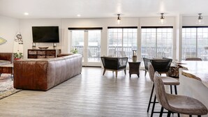 A spacious living area with a large sofa, a dining table with chairs, and a TV mounted on the wall. - SCP Depoe Bay (Depoe Bay)