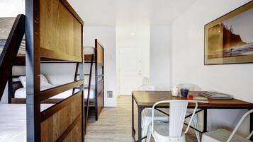 Una habitación con literas, una mesa de comedor con sillas y un cuadro en la pared.