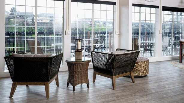 A spacious room with large windows, wicker furniture, and a round table. - SCP Depoe Bay (Depoe Bay)