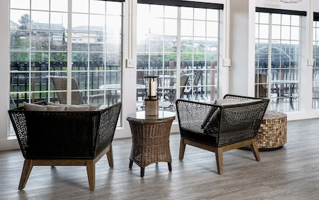A spacious room with large windows, wicker furniture, and a round table.