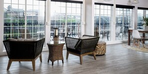 A spacious room with large windows, wicker furniture, and a round table. - SCP Depoe Bay (Depoe Bay)