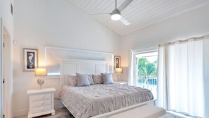 Un dormitorio con cama, mesitas de noche, un banco y vistas al exterior.