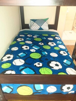 Una cama con una colcha de estampado de balón de fútbol azul y una almohada geométrica.