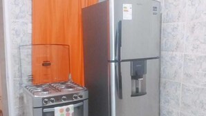 A compact kitchen with a gas stove, oven, and a stainless steel refrigerator. - Hidden Garden - Hostel (Cusco)