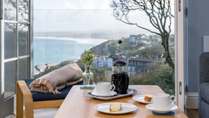A cozy seating area with a table set for tea, a coffee maker, and a view of the ocean. - A stunning apartment with breathtaking views, situated in a select development. (Carbis Bay)