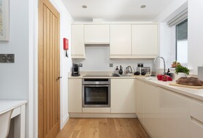 Una cocina moderna con armarios blancos, horno integrado y ventana.