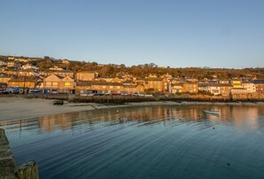 Un pueblo costero con edificios a lo largo del paseo marítimo, una playa de arena y un pequeño bote.