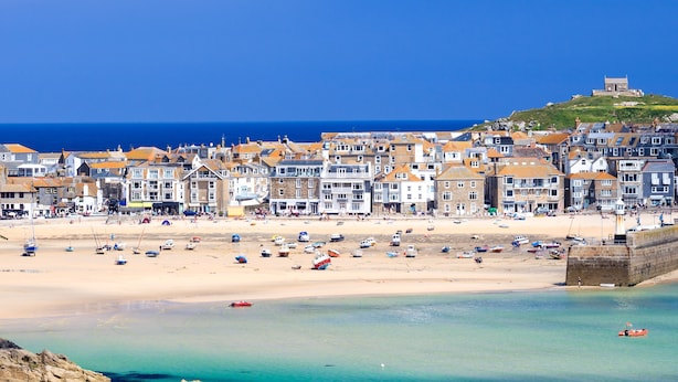 Eine Küstenstadt mit sandigem Strand, Booten und Gebäuden entlang der Küste.